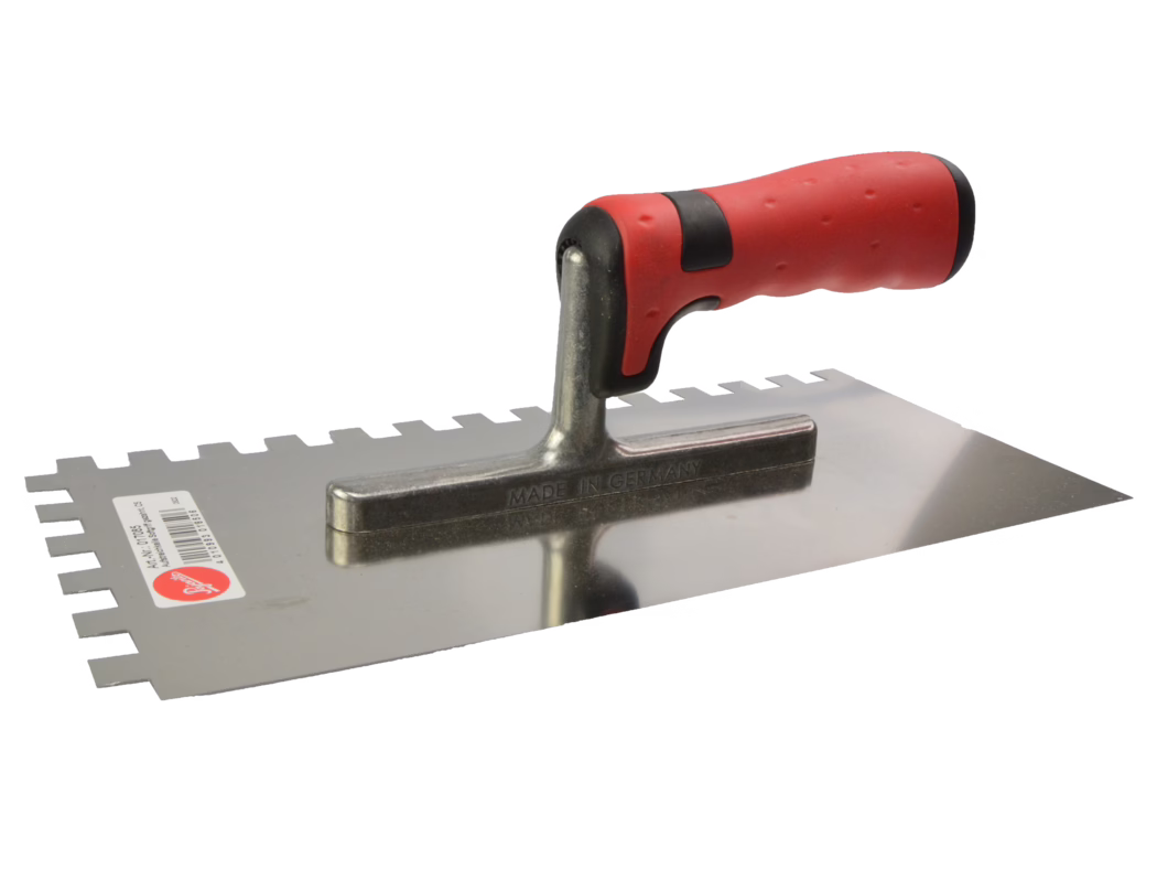 Arturo Tools_Pajarito Lijmspaan Een gekartelde roestvrijstalen troffel met een ergonomisch rood-zwart rubberen handvat ligt op een witte achtergrond; het blad met vierkante tanden en de metalen bevestiging zijn zichtbaar, met een subtiele reflectie op het glanzende metaal.